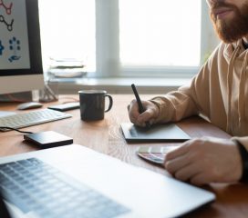 Creating graphic design Close-up of busy brand designer sitting at desk and creating graphic design using digitizer and color palette